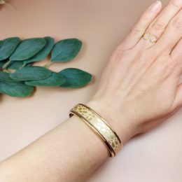 bracelet jonc doré avec lanière cuir nude porté au poignet d'une femme