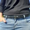 Ceinture fine en cuir noir à maillons portée sur un jean