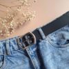 ceinturon noir en cuir large de 4 cm passé sur un pantalon
