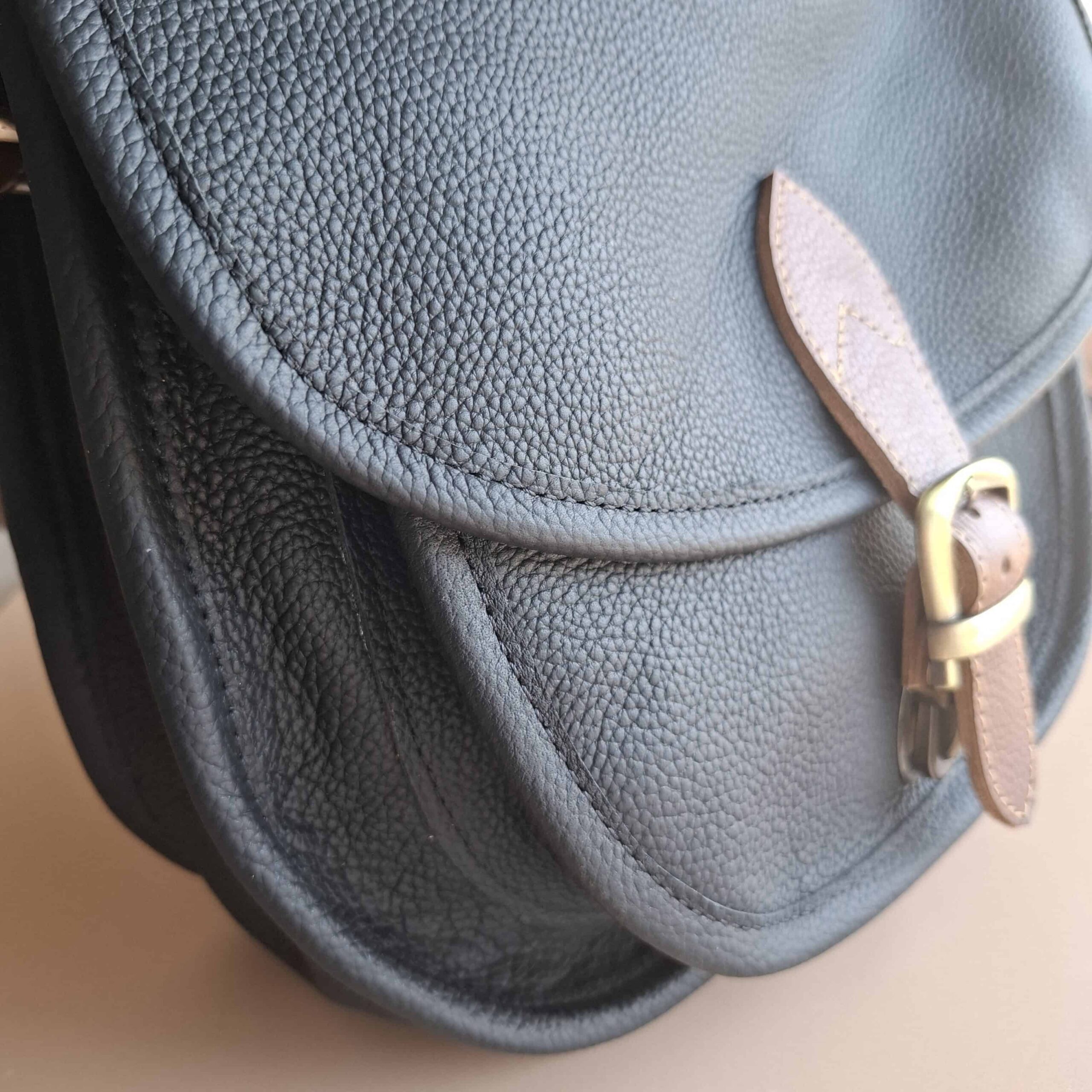 Gros plan sur le grain du cuir noir du sac Simone — patte de fermeture cuir naturel et boucle laiton