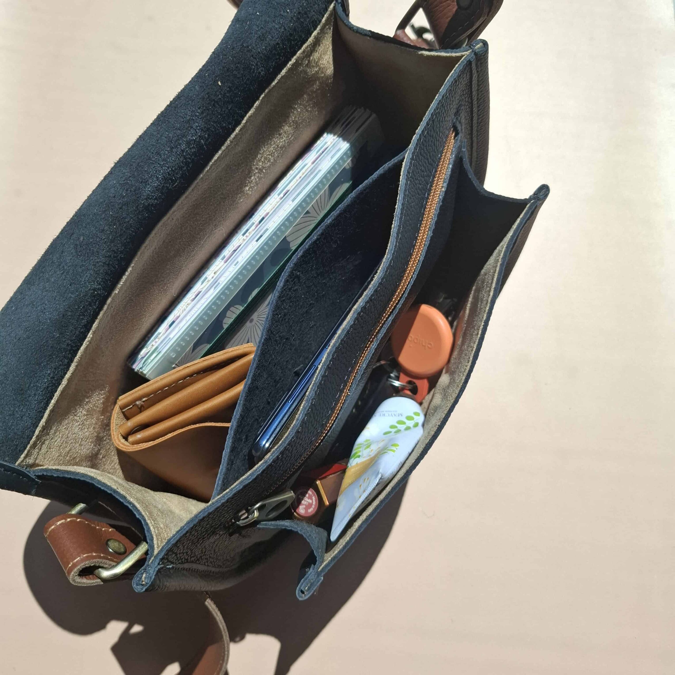 Intérieur du sac Simone grainé chargé — portefeuille, carnet, téléphone, compartiments séparés