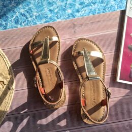 Sandales tropéziennes dorées Inès posées au bord de la piscine en été